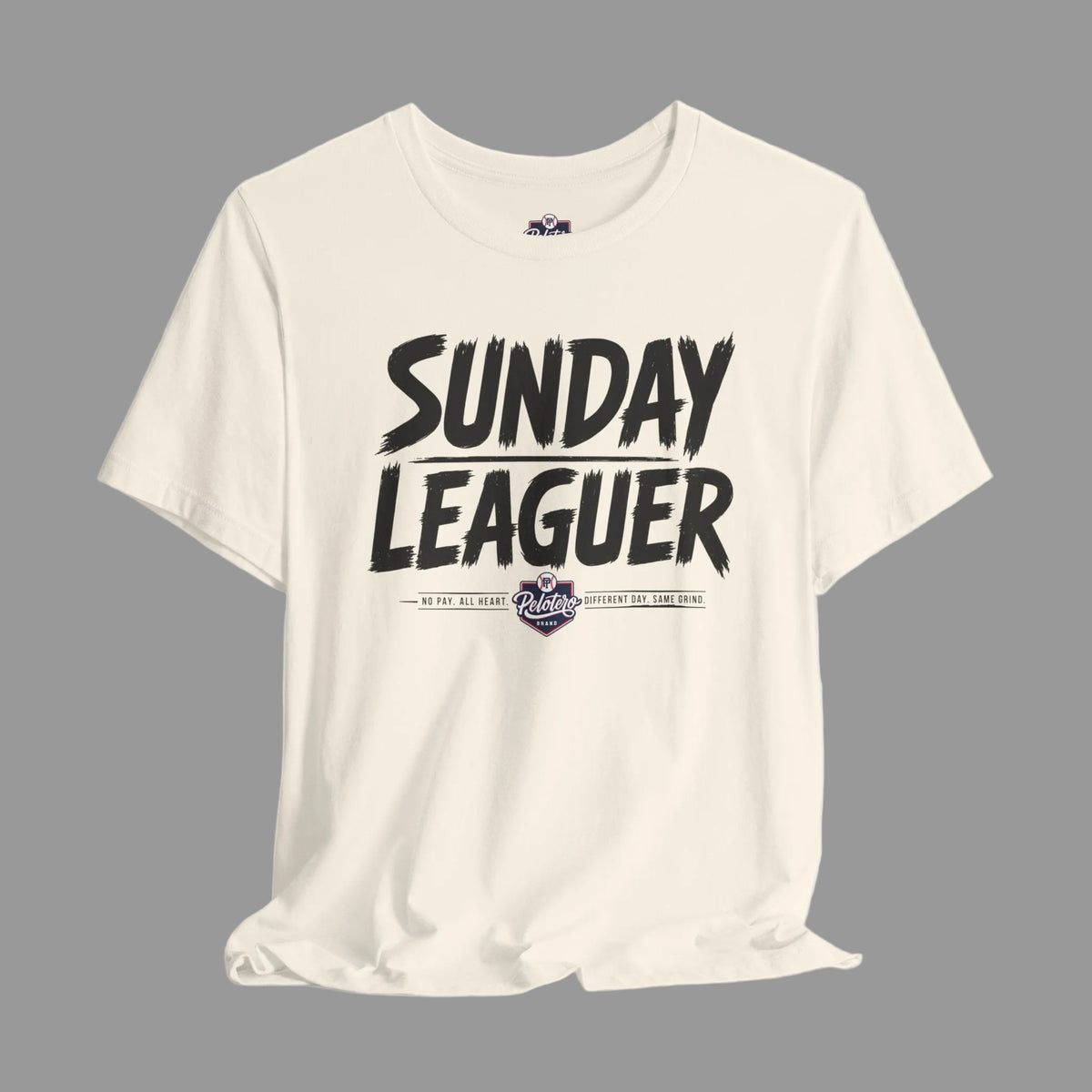 An off-white crewneck t-shirt featuring a black distressed graphic that reads 'SUNDAY LEAGUER' with a small purple and white 'Pirates' logo underneath, displayed on a light gray gradient background.