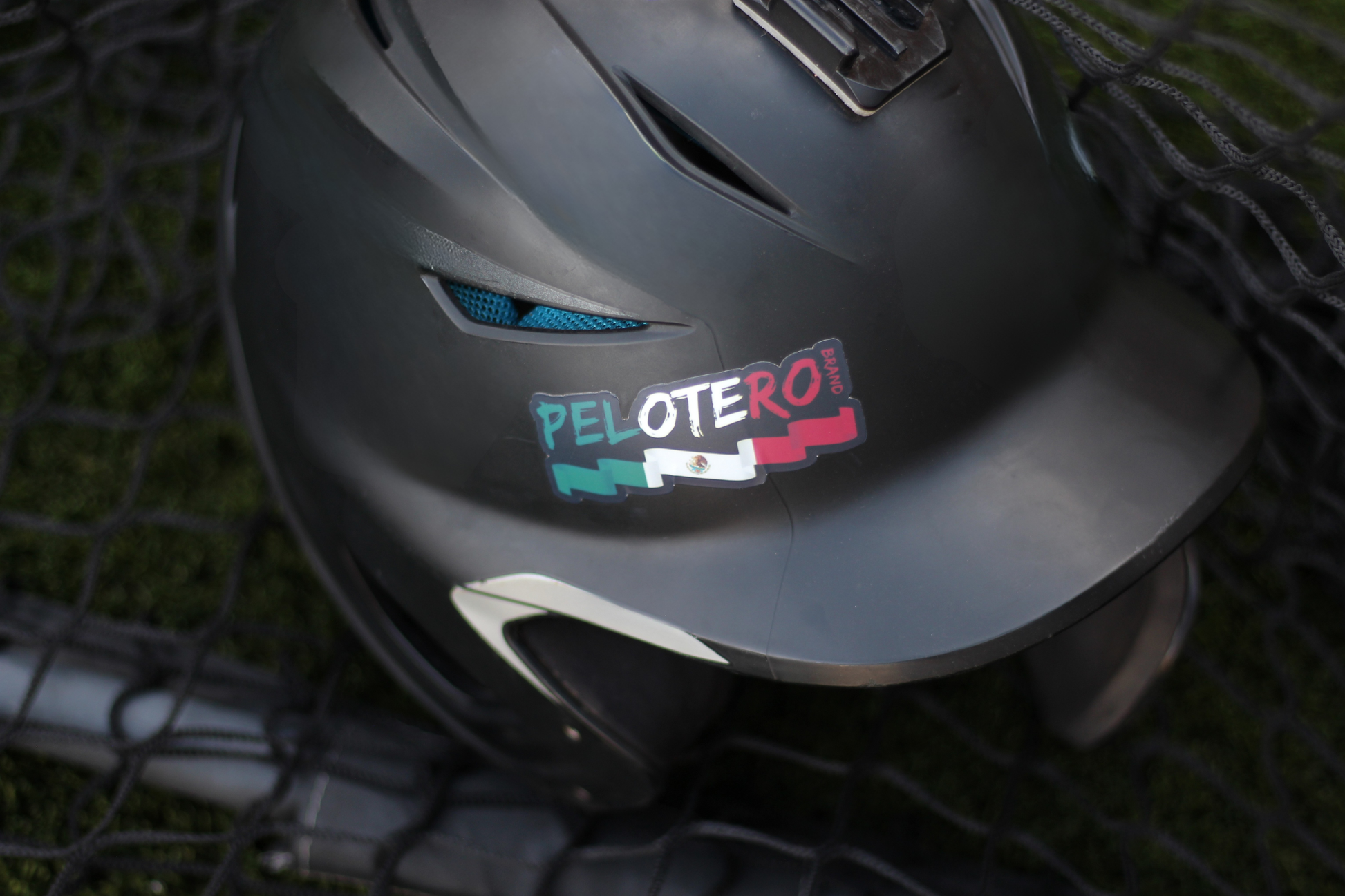 Gray helmet with a 'Pelotero' sticker on a textured surface